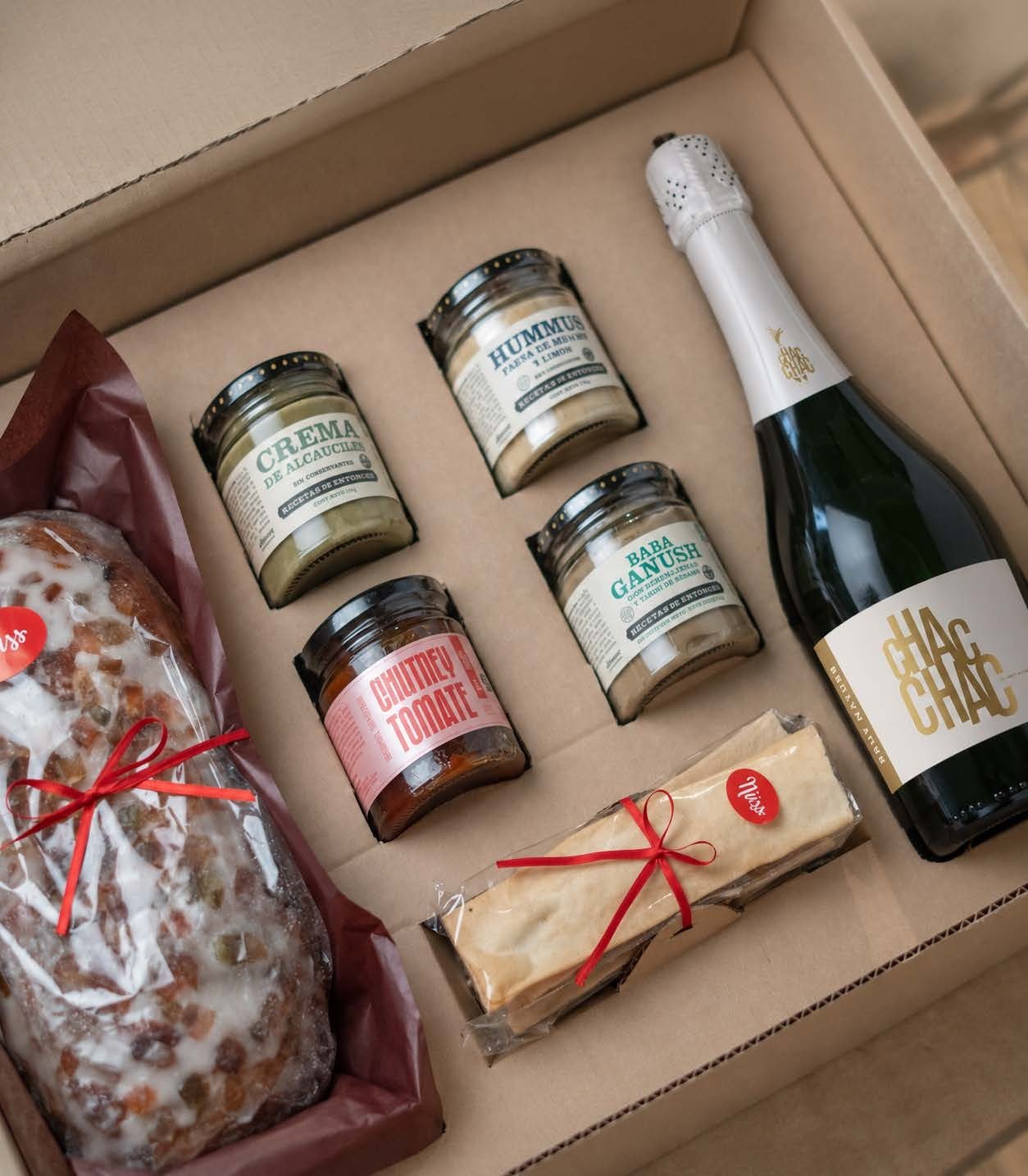 Caja abierta con panettone, cintas, cuatro conservas y el Brut Nature